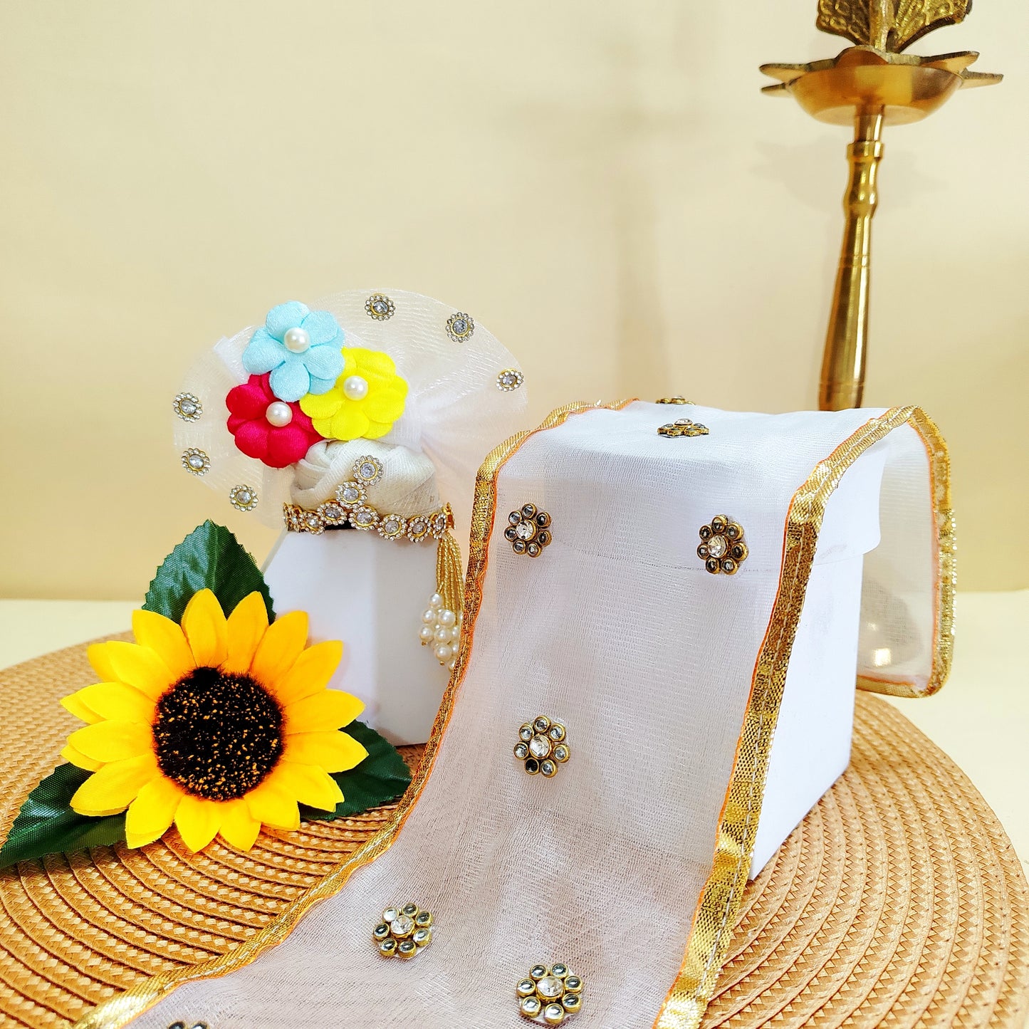 Decorative Mukut with colorful flowers and a sunflower, placed on a textured surface.