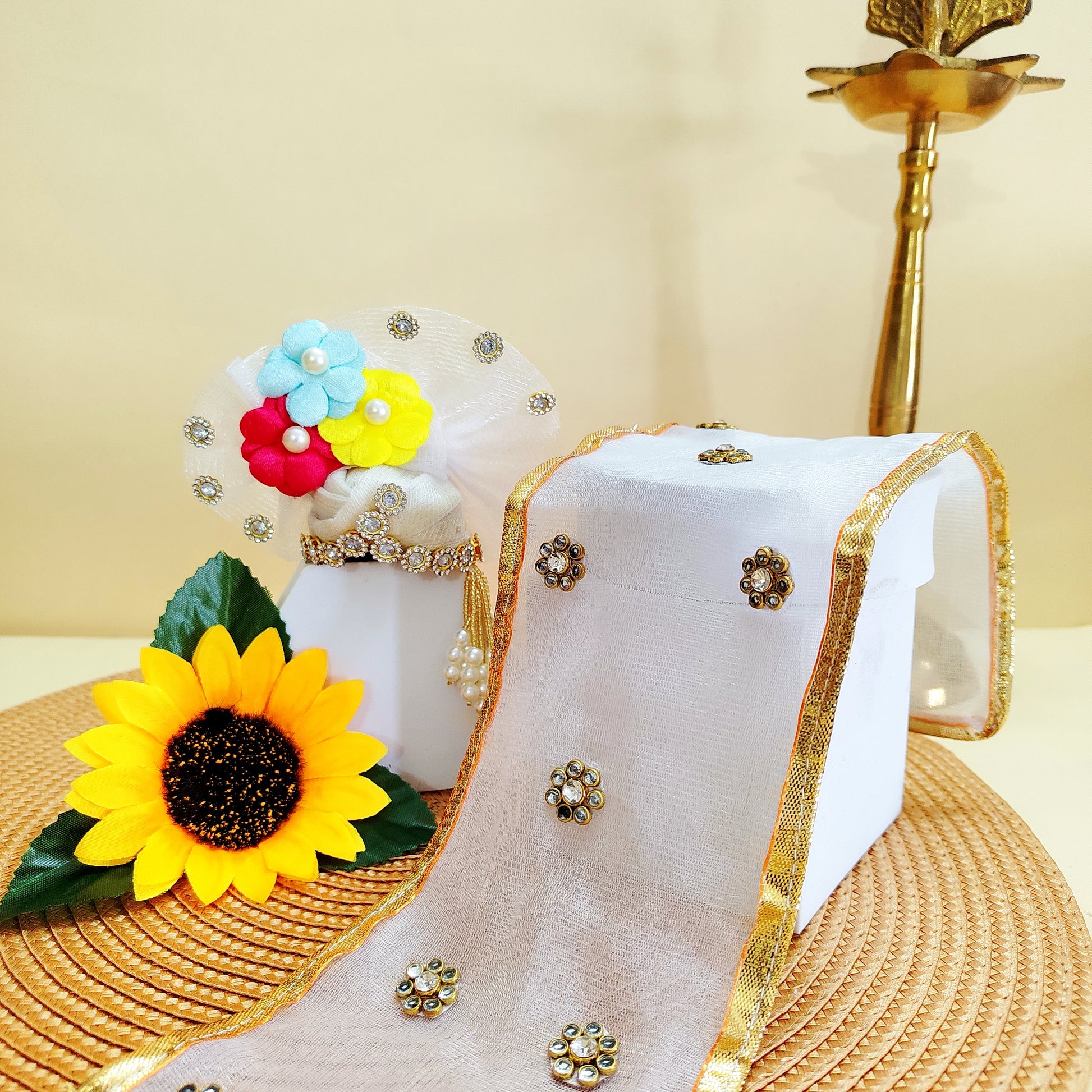 Decorative Mukut with colorful flowers and a sunflower, placed on a textured surface.