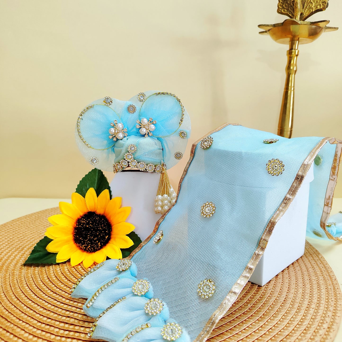 Light blue Mukut Laddu Gopal with gold border and decorative elements on a beige background