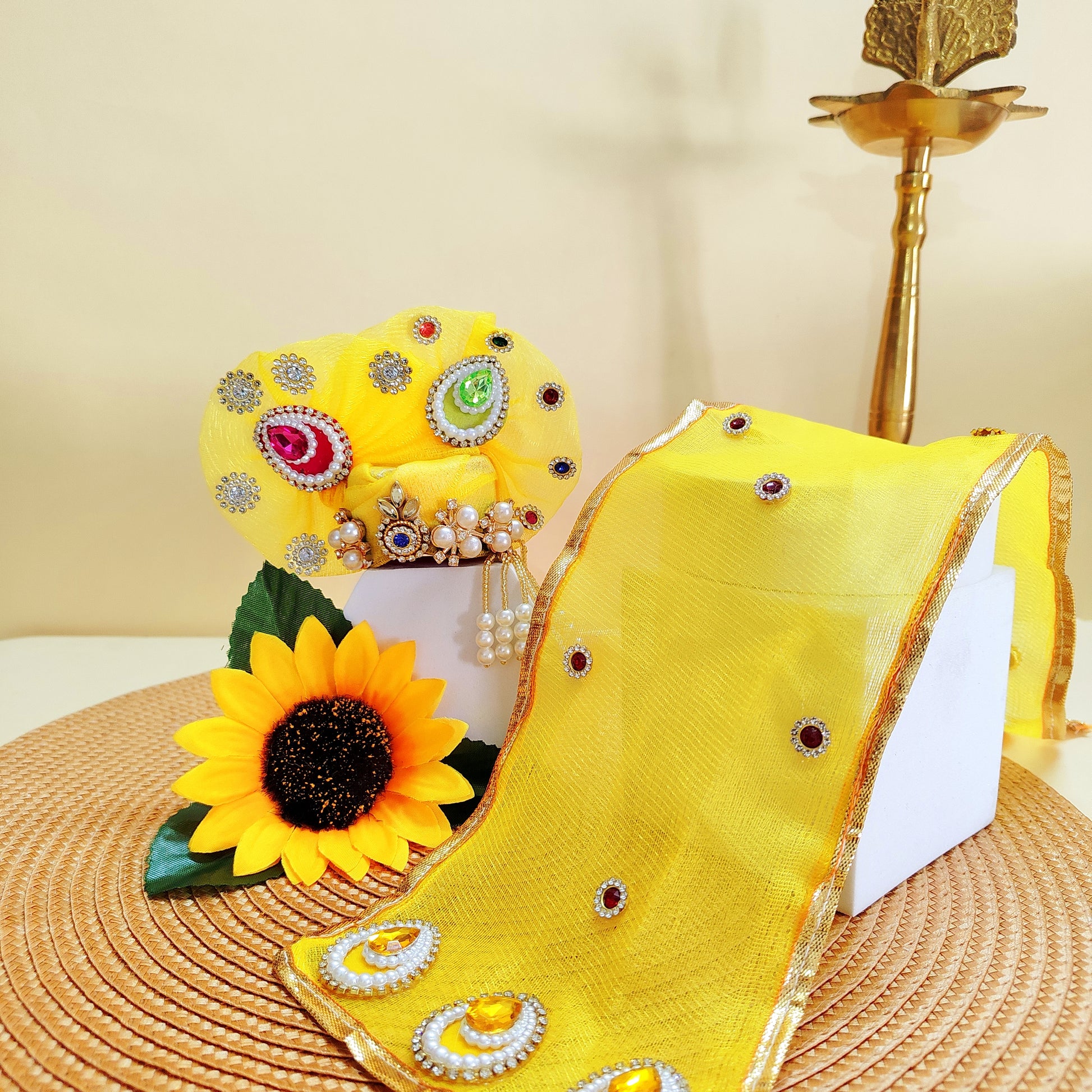 Yellow decorative Pagdi with sunflower and jewelry on a beige background