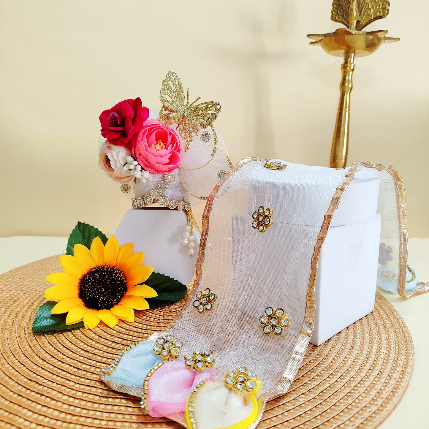 Decorative Crown Laddu Gopal with flowers, jewelry, and a box on a textured surface.